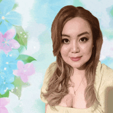 a woman in a yellow shirt is standing in front of a floral background