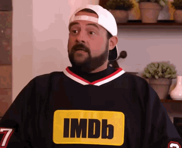 a man with a beard wears a black jersey with imdb on it