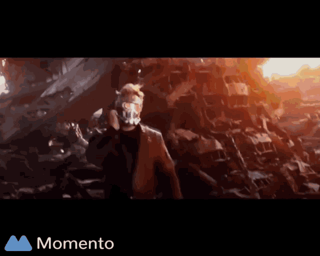 a man in a suit is standing in front of a fire and the word momento is on the bottom right