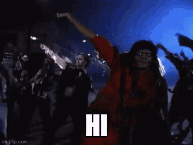 a man in a red jumpsuit is dancing in front of a crowd and the word hi is on the bottom