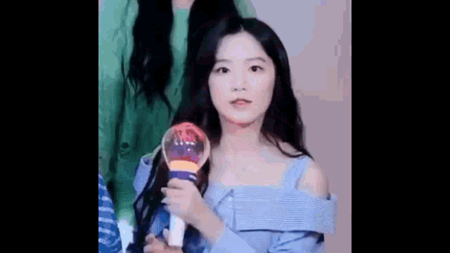 a girl in a blue dress is holding a light stick in her hand .