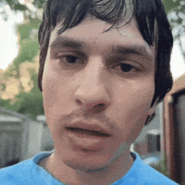 a close up of a man 's face with wet hair and a blue shirt