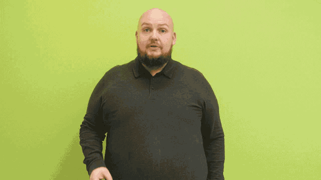 a bald man with a beard wearing a black shirt is making a gesture with his hand