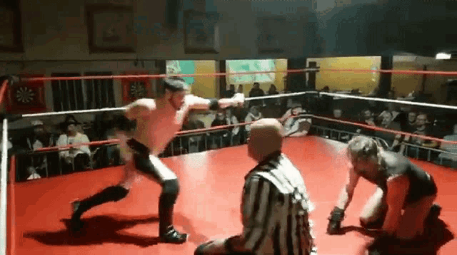 two men are fighting in a boxing ring with a referee watching