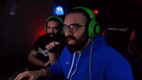 a man with a beard wearing green headphones is sitting in front of a computer .