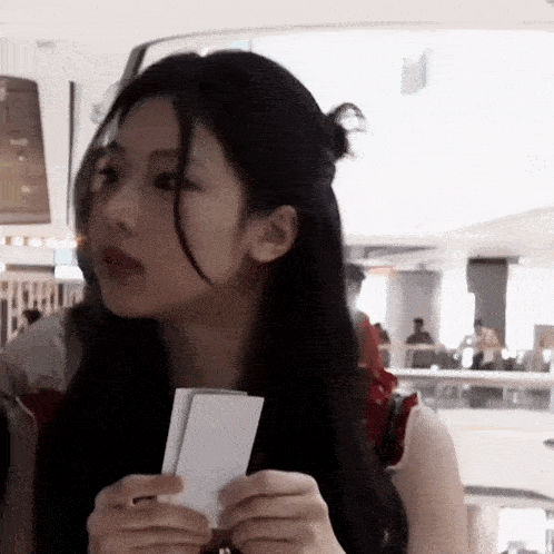 a woman with long black hair is holding a piece of paper .