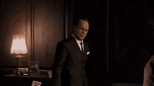a man in a suit and tie talks to another man in a vest