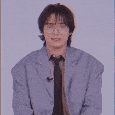 a man wearing glasses and a suit is sitting down