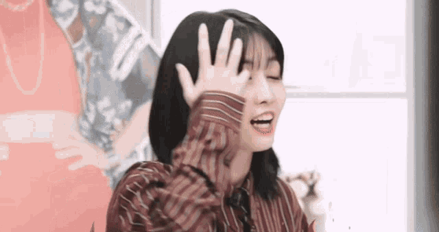 a young woman is making a funny face with her hand on her face .