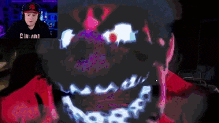 a man wearing headphones and a hat is playing a video game with a glowing face behind him .