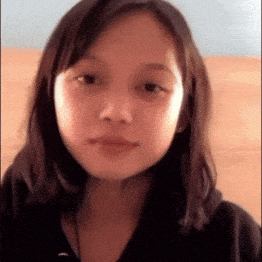 a close up of a young girl 's face with a black shirt on .
