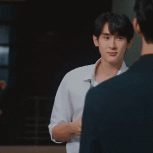 a man in a white shirt and tie is talking to another man in a suit .