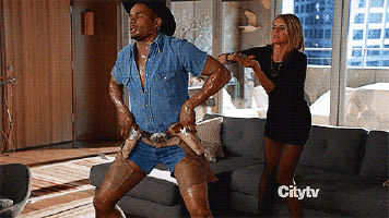 a man dressed as a cowboy is dancing in a living room with a woman behind him and the words citytv on the bottom