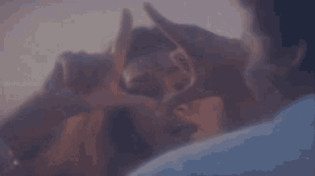 a man and a woman are touching each other 's faces with their hands in a blurry photo .
