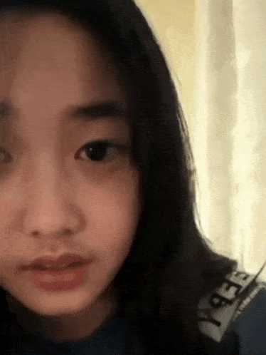 a close up of a young girl 's face with long hair looking at the camera