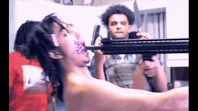 a man is holding a gun with a knife in his mouth while another man looks on