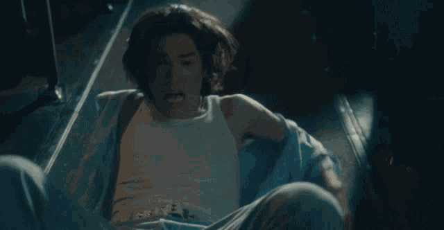 a young man in a white tank top is screaming