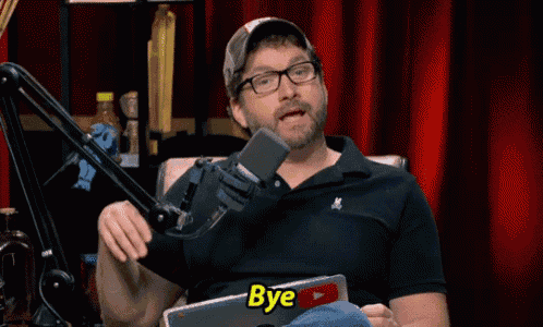 a man sitting in front of a microphone with the word bye on his shirt