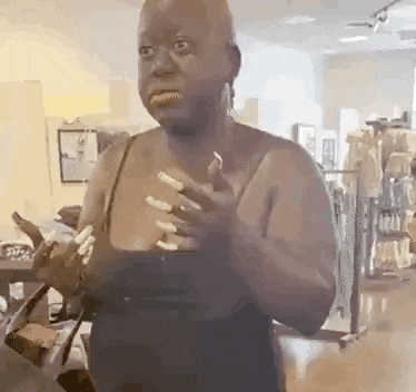 a woman with long nails is standing in a room holding her hands together .