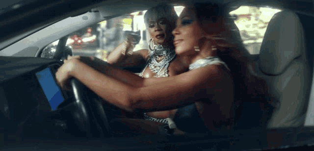 two women are sitting in a car and one is looking at the dashboard