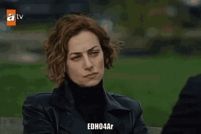 a woman sits on a bench in front of a tv screen that says atv