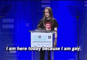 a woman stands at a podium speaking into a microphone and says i am here today because i am gay
