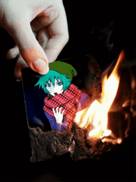 a person is burning a picture of a girl with green hair and a green hat