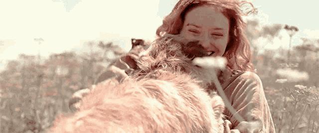 a woman is playing with a dog in a field .