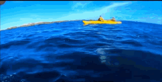 a person in a yellow kayak is floating on top of a blue ocean