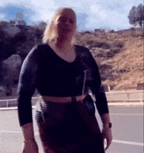 a woman in a black top and brown skirt is walking down a street