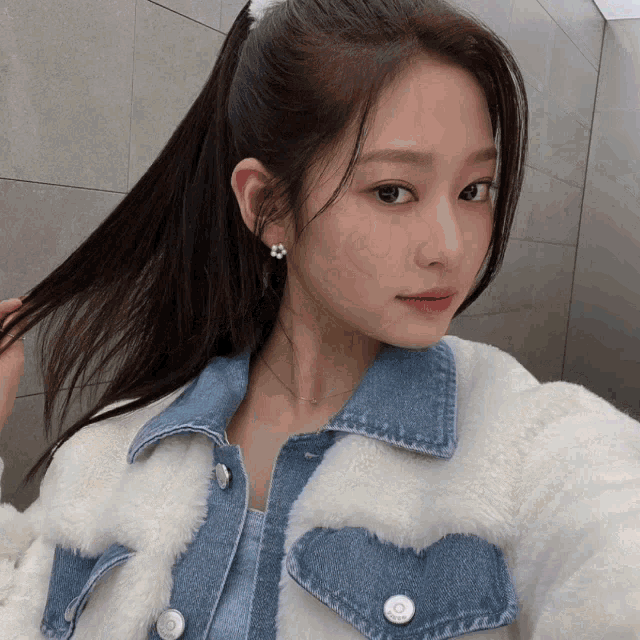 a woman in a ponytail is wearing a white jacket