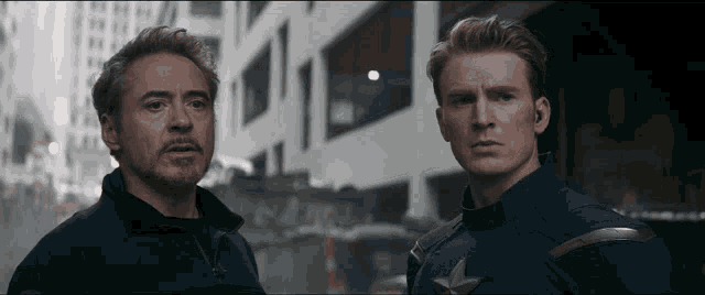 tony stark and captain america are standing next to each other in front of a building