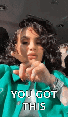 a woman in a green jacket is making a heart shape with her fingers and says `` you got this '' .