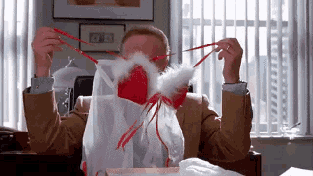 a man in a suit is holding a red and white lingerie set in front of his face