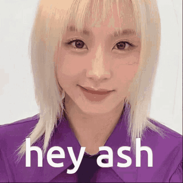 a woman with blonde hair is wearing a purple shirt and tie and says hey ash