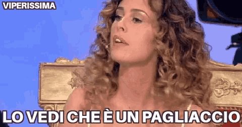 a woman with curly hair is sitting on a throne and says lo vedi che e un pagliaccio .