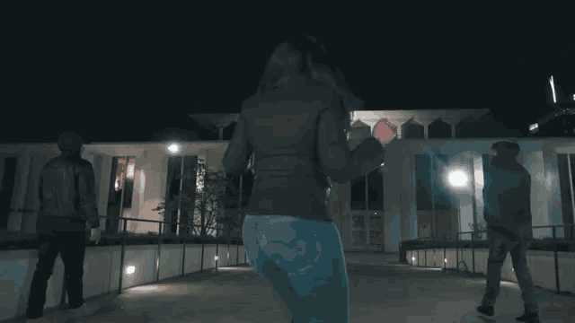 a woman is dancing in front of a building with the word bbc on it