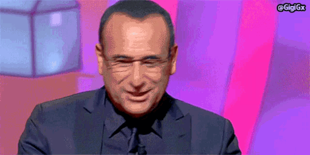 a man in a suit and tie is smiling in front of a purple background with the hashtag gigigx