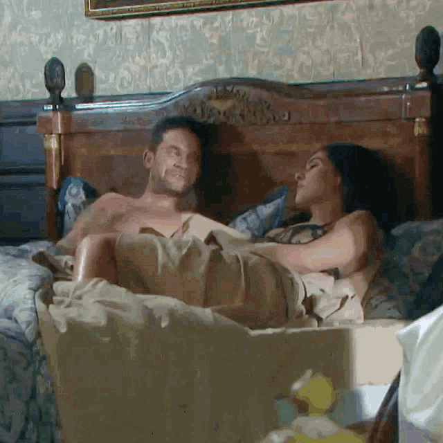 a man and a woman are laying in a bed together