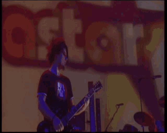 a man playing a guitar with a skull shirt on