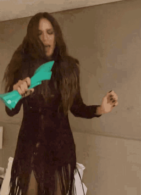 a woman in a purple dress is dancing with a green object in her hand