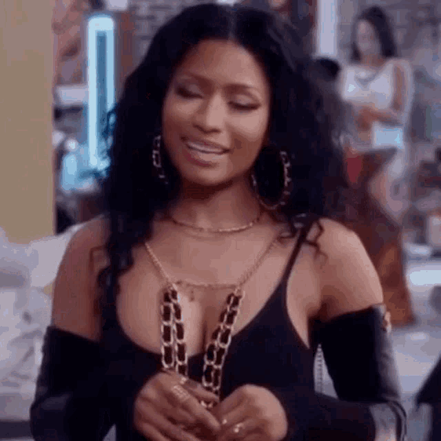 nicki minaj is wearing a black top and a gold chain necklace .