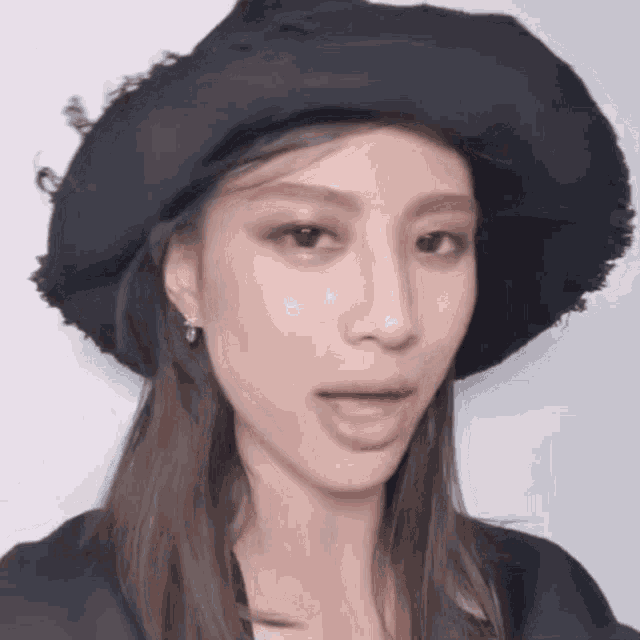 a woman wearing a black hat is making a face