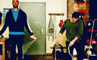 two men are standing next to each other in a room and one is using a vacuum cleaner ..