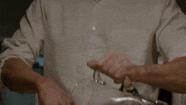 a man in a white shirt pours a glass of liquid from a pitcher