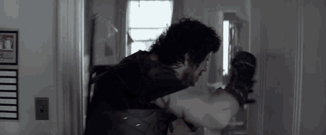 a man wearing boxing gloves is punching another man in a room .