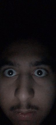 a close up of a man 's face with his eyes wide open in the dark