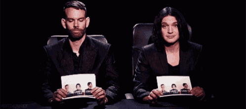 a man and a woman are sitting at a table holding a picture of a man 's mug shot .