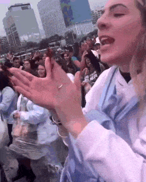 a woman with a ring on her finger applauds in front of a crowd of people