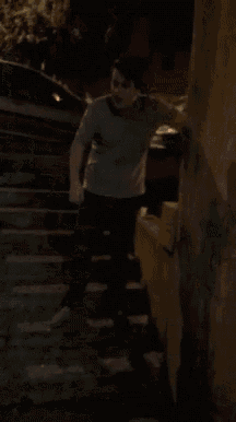 a man in a white shirt is walking down a set of stairs at night